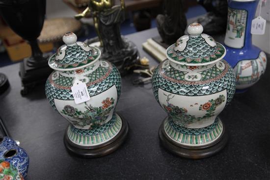 A pair of Chinese famille verte baluster vases and covers, late 19th century, 29.5cm, later drilled for lamp fittings, wood stands